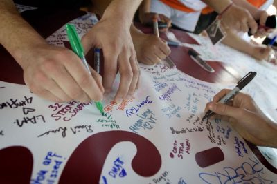 Participants sign the 3.2 for 32 banner. 
